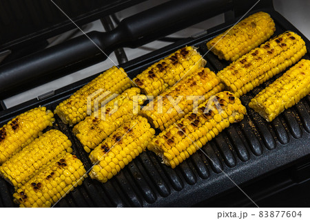 Grilled sweet corn cobs on grill surface 83877604