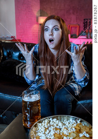 Emotional beautiful woman watching football, sitting in living r 83878267