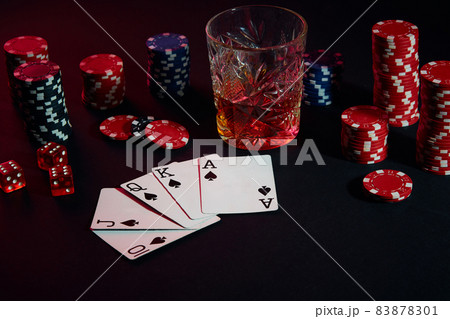 Cards of poker player. On the table are chips and a glass of cocktail with whiskey. Combination of cards - Royal Flush 83878301
