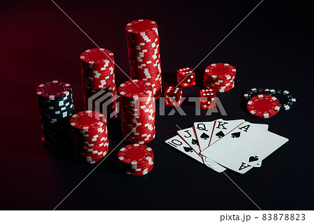 Red and black chips for gambling and playing cards on black background 83878823