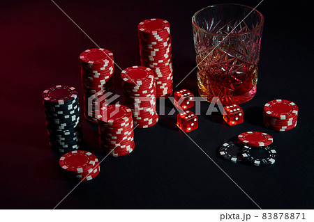 Poker chips and wine glass of cognac on dark table. Gambling 83878871