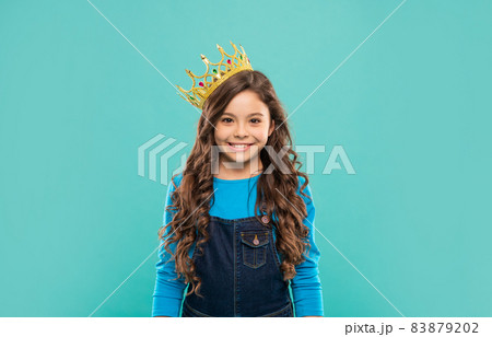 happy child with curly hair in queen crown on blue background, selfishness happy child with curly hair in queen crown on blue background, selfishness 83879202