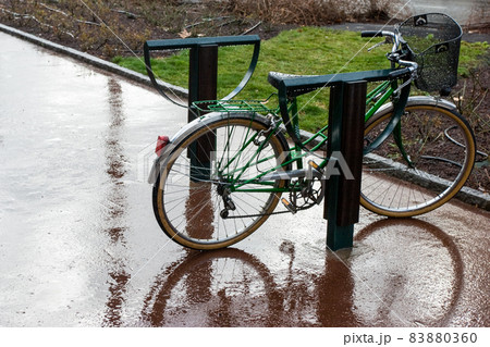 Bicycle left in the rain on the street 83880360