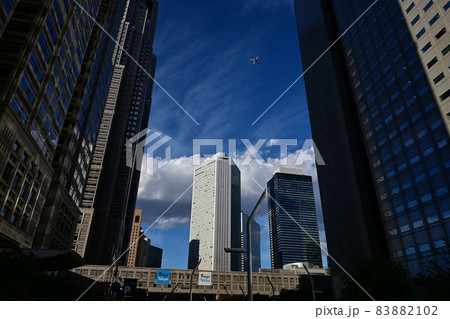 新宿高層ビル群　上空を飛行機が飛ぶ　秋の高い大空と白い雲 83882102