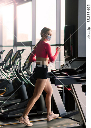 Coronavirus covid-19 prevention, fitness girl with a medical mask posing in gym. Fighting viruses. Coronavirus covid-19 prevention, fitness girl with a medical mask posing in gym. Fighting viruses. 83883496