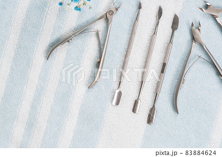 Manicure tools are laid out on a white-blue striped towel, studio photo Manicure tools are laid out on a white-blue striped towel, studio photo 83884624