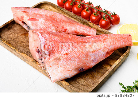 Red sea perch or big eyed fish, on wooden serving board, on white stone table background Red sea perch or big eyed fish, on wooden serving board, on white stone table background 83884807
