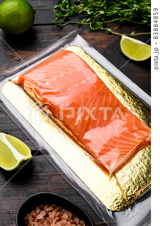 Fresh raw salmon fish steak in vacuum pack, with herbs, on old dark wooden table background 83884859