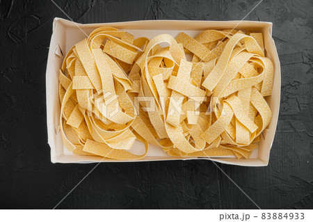 Raw pappardelle, on black dark stone table background, top view flat lay 83884933