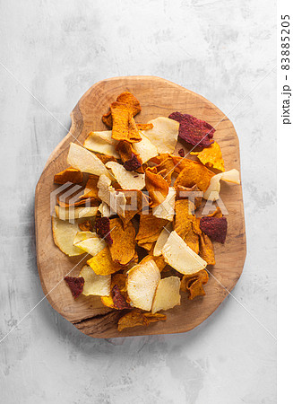 Vegetable chips laid on a wooden board on a concrete background 83885205