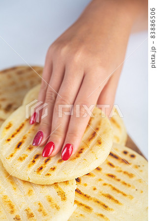 Woman holds Traditional Venezuelan food arepa made from cornmeal Woman holds Traditional Venezuelan food arepa made from cornmeal 83886506