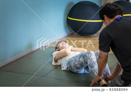 パーソナルトレーナーと腹筋をする女性(男性) パーソナルトレーナーと腹筋をする女性(男性) 83888094