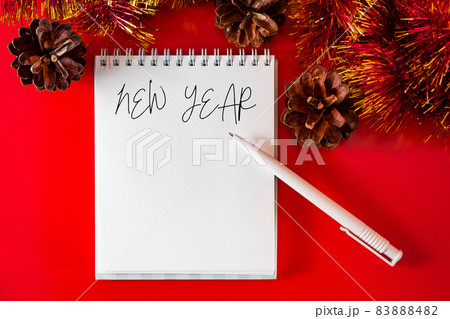 Blank notebook and pen on the background of Christmas decorations. Layout for plans for the new year. Blank notebook and pen on the background of Christmas decorations. Layout for plans for the new year. 83888482