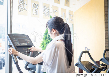 ウォーキングマシンのパネルを操作する女性 83893118