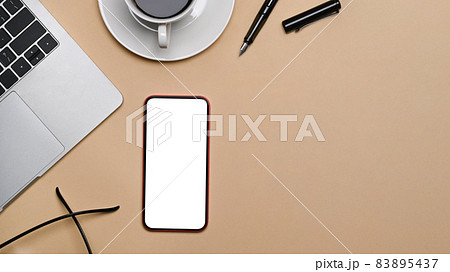 Smart phone with blank screen and laptop computer on beige background. 83895437