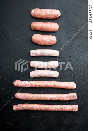 Assorted fresh raw pork, beef and chicken sausages, top view, on black background 83898339