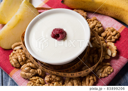 yogurt in a pial decorated with raspberries, nuts and fruits, concept of healthy eating yogurt in a pial decorated with raspberries, nuts and fruits, concept of healthy eating 83899206