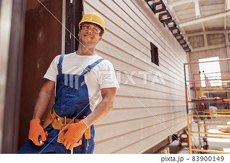 Joyful builder standing by door of prefabricated container house Joyful builder standing by door of prefabricated container house 83900149