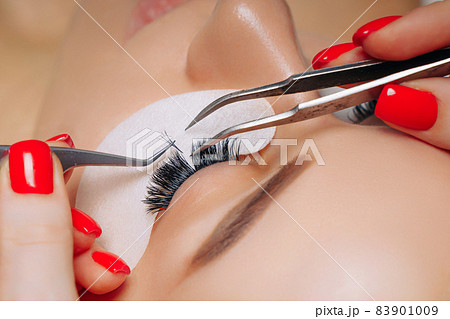 Eyelash Extension Procedure. Woman Eye with Long Eyelashes. Close up, selective focus. 83901009