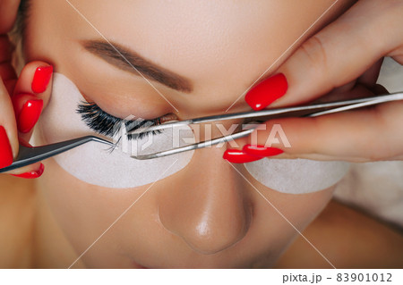 Eyelash Extension Procedure. Woman Eye with Long Eyelashes. Close up, selective focus. 83901012