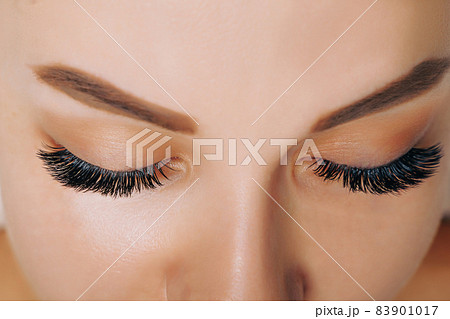 Eyelash Extension Procedure. Woman Eye with Long Eyelashes. Close up, selective focus. 83901017