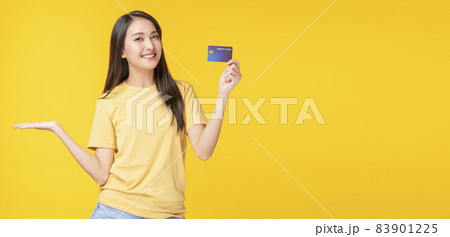 Cheerful young woman wearing casual clothes while holding credit card mockup in own hand Cheerful young woman wearing casual clothes while holding credit card mockup in own hand 83901225