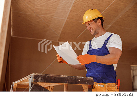 Joyful builder studying architectural plan at construction site 83901532