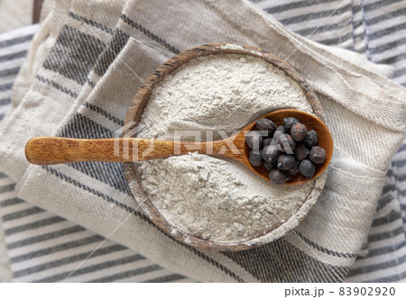 Wooden bowl of black chickpea flour and spoon of beans top view 83902920