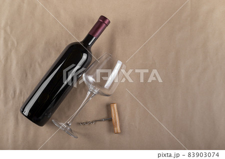 Wine bottle, glass and corkscrew on a brown background. Space for text. 83903074