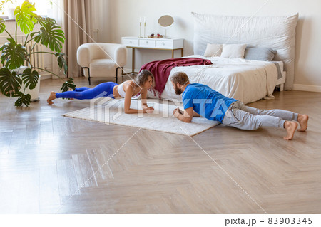 Middle-aged couple working out at home. Plank position. The concept of a healthy lifestyle and maintaining oneself in shape after the age of 40. Middle-aged couple working out at home. Plank position. The concept of a healthy lifestyle and maintaining oneself in shape after the age of 40. 83903345