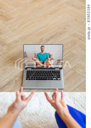 Couple meditates under the guidance of an online trainer in front of a laptop monitor. The concept of mental health and yoga practices using modern technologies. 83903384