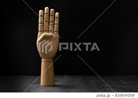 Picture of a wooden hand showing hand signal. The hand is placed on a wooden table with black background Picture of a wooden hand showing hand signal. The hand is placed on a wooden table with black background 83904009