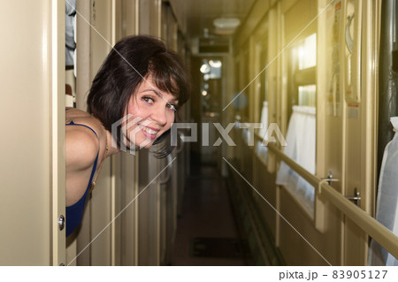 Smiling brunette woman playfully looks out of her compartment on the train 83905127