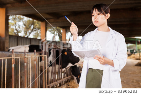 Professional female vet standing near calves barn in livestock farm 83906283
