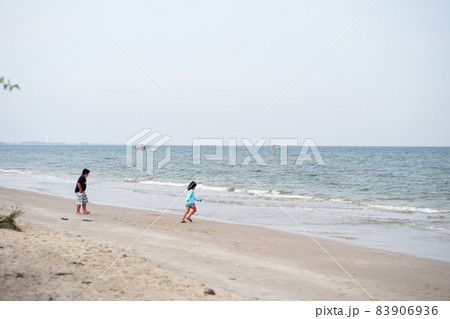 Seascape with fishing boat floating in the sea with blurred foreground of little boy and girl playing on the beach Seascape with fishing boat floating in the sea with blurred foreground of little boy and girl playing on the beach 83906936