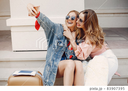 Elegant and stylish girl sitting with a suitcase Elegant and stylish girl sitting with a suitcase 83907395