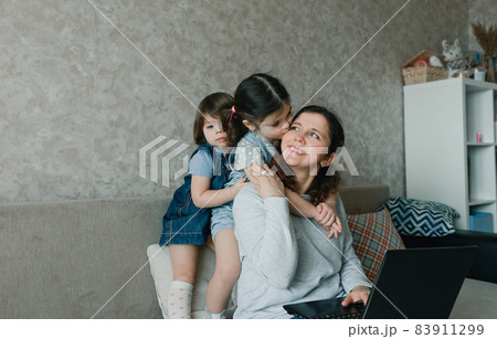 mom works at home on the computer surrounded by small children 83911299