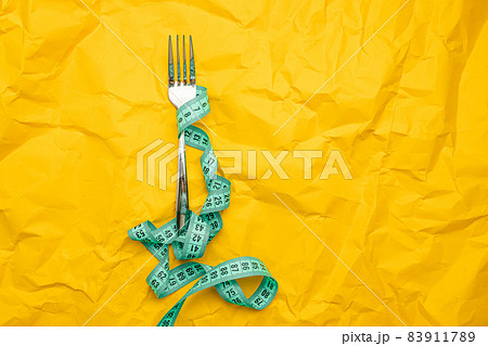 Iron fork with measuring tape with a space paper for text. Crush paper. Diet and healthy food concept. Healthy lifestyle. 83911789