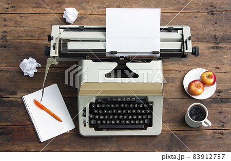 Vintage typewriter with the Russian alphabet and a sheet of paper on an old table, a notebook on a spring and a pen, apples on a plate Vintage typewriter with the Russian alphabet and a sheet of paper on an old table, a notebook on a spring and a pen, apples on a plate 83912737