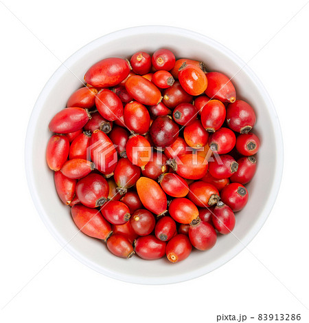 Fresh wild rose hips, in a white bowl. Also known as rose haw or rose hep. Ripe and intense red fruits, used for herbal teas, jam and can be eaten raw. One of the richest vitamin C sources in plants. 83913286