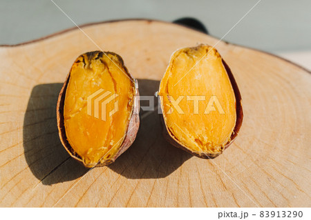 Sweet potato cut into half on wooden plate. 83913290