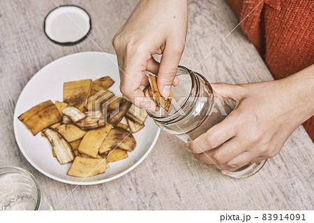 A person making banana peel fertilizer with banana cuts. Putting small pieces of banana skin into the glass jar and pouring water 83914091