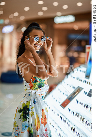 Shopping. Pretty smiling asian woman choosing sunglasses in showcase Shopping. Pretty smiling asian woman choosing sunglasses in showcase 83914961