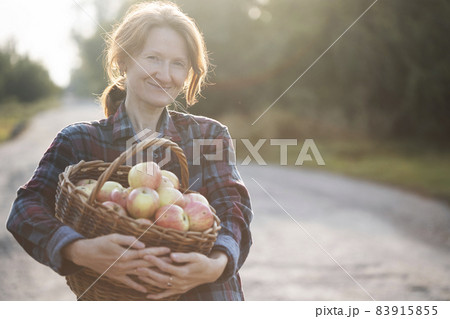 girl holds  basket  with juicy apples in the garden 83915855