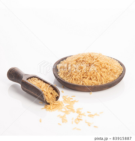 Brown rice on wooden plate and spoon. Isolated on white backround. Brown rice on wooden plate and spoon. Isolated on white backround. 83915887