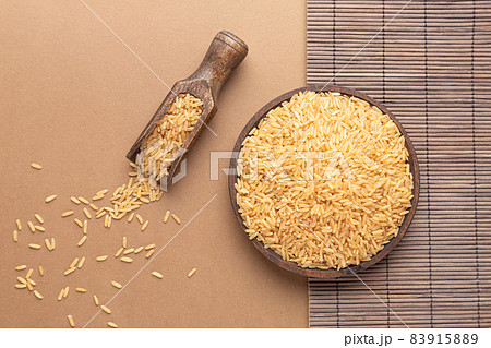 Brown rice on wooden plate and spoon on brown and wood backround. Flat lay composition. 83915889