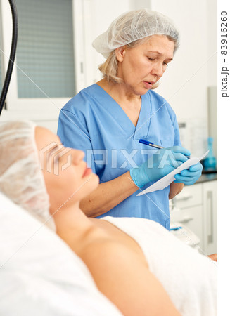 Skillful cosmetologist consulting young woman in medical esthetic office 83916260