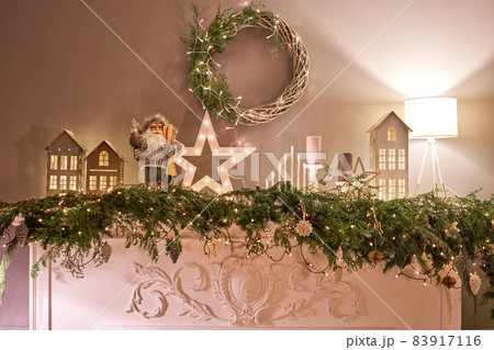 Decorated fireplace. Christmas tree. Close-up a small house, Cones, garland, and other Christmas tree toys. light from the garlands 83917116