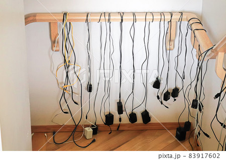 Numerous cables hang from a stair rail 83917602