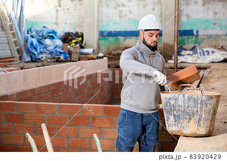 Builder working with red brick 83920429